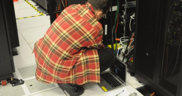 Technician with a laptop working on a server rack in a data center