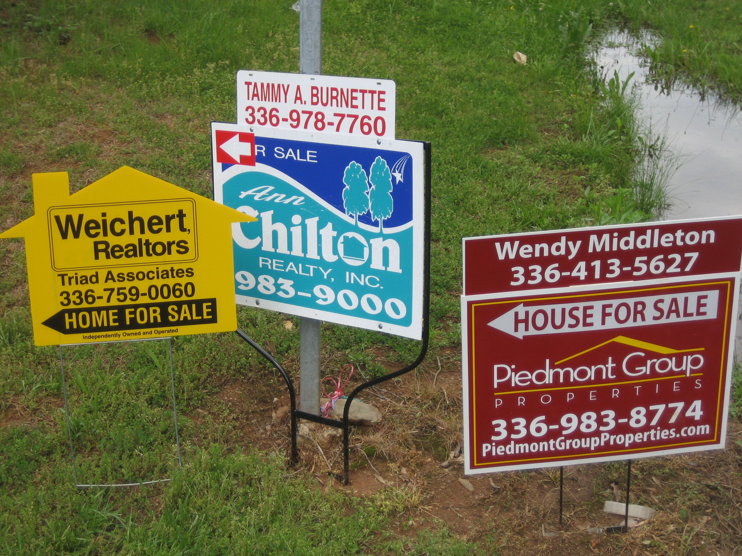 Houses for sale sign in front of a suburban home